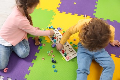 Cute little children playing with game Fishing for Numbers on puzzle mat. Kindergarten activities for learning mathematics