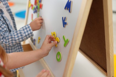 Little children learning alphabet with magnetic letters on board in kindergarten, closeup