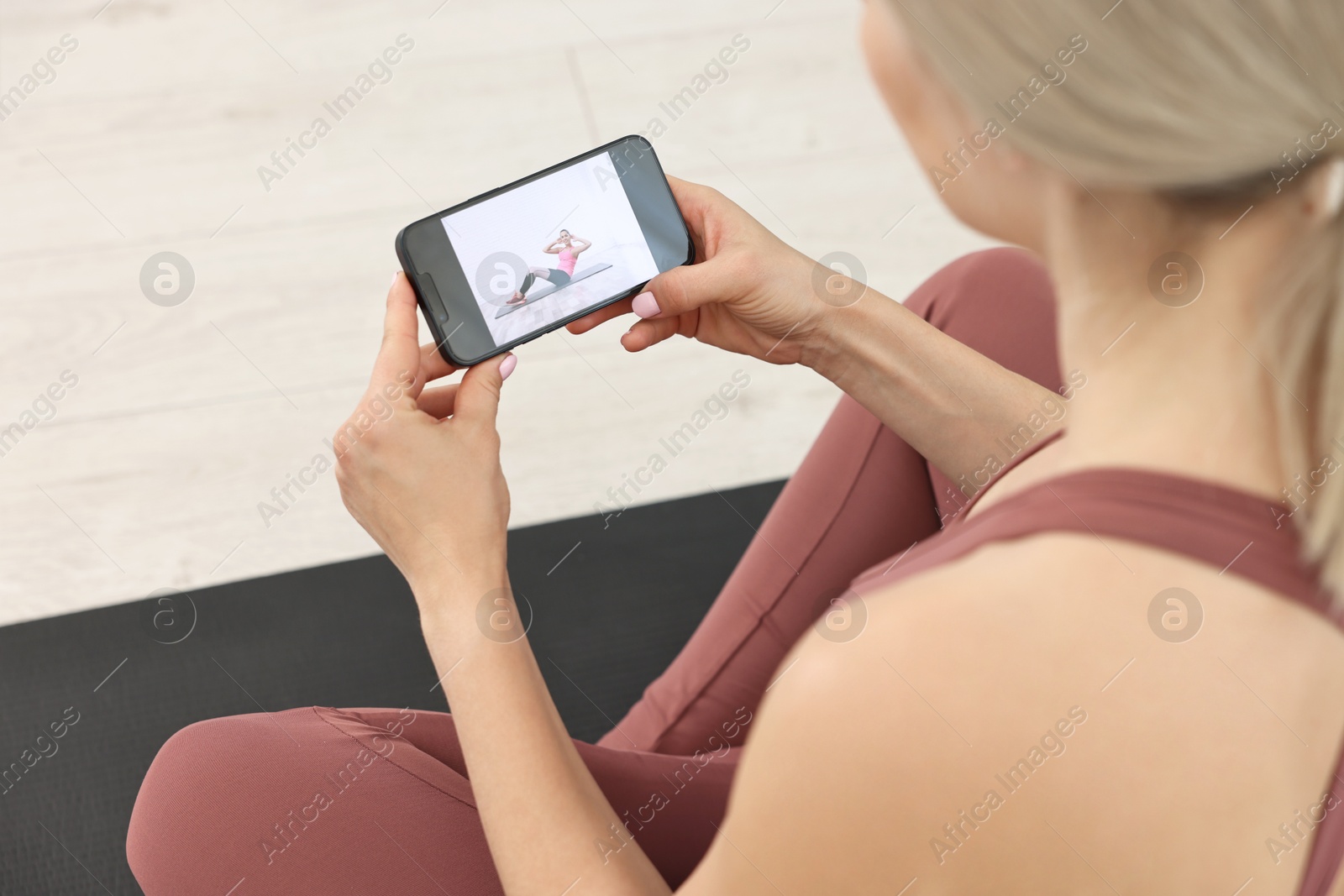 Photo of Online fitness trainer. Woman watching tutorial on smartphone indoors, above view
