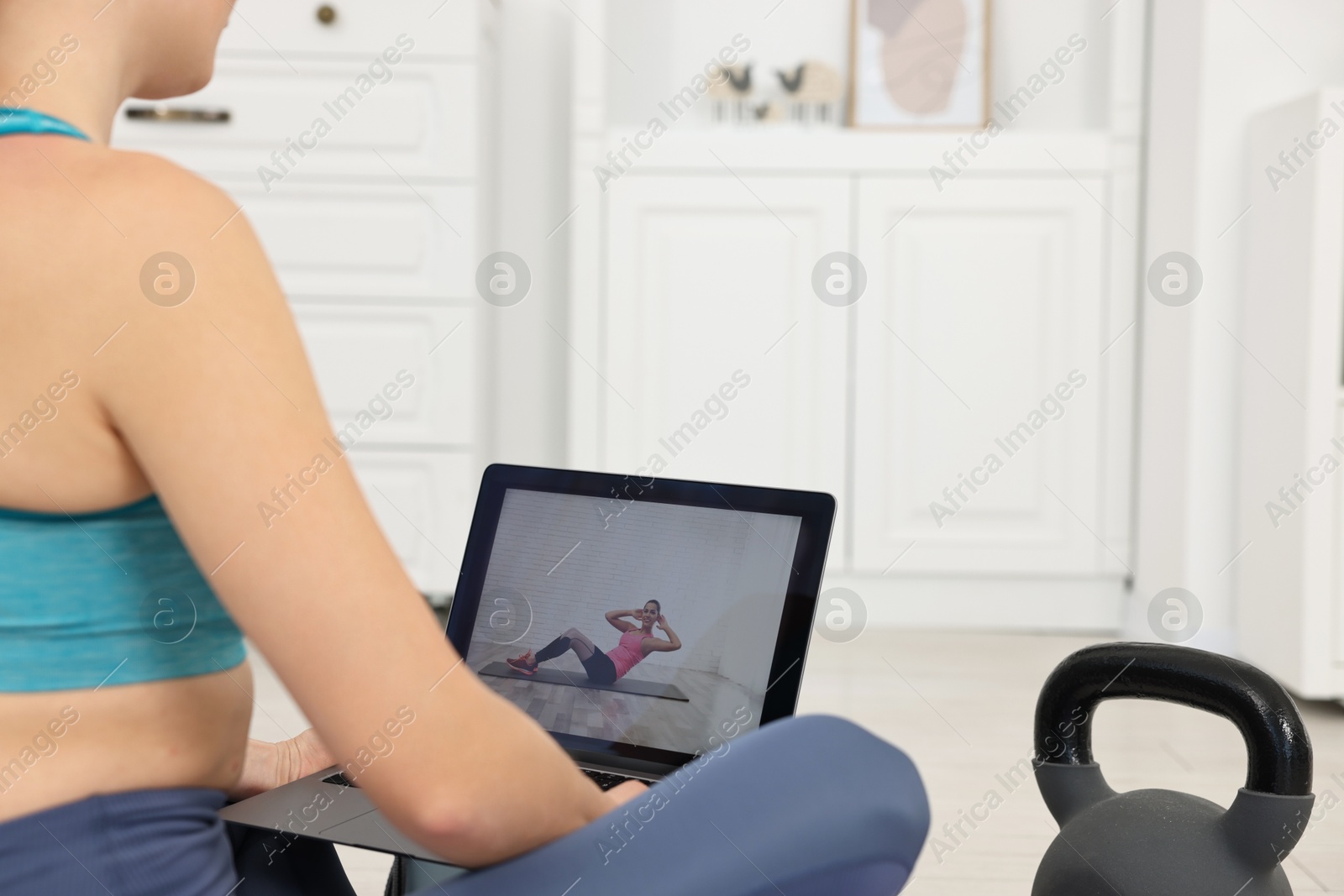 Photo of Online fitness trainer. Woman watching tutorial on laptop at home, closeup