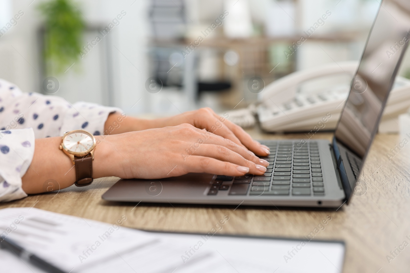 Photo of Secretary working with laptop at table in office, closeup