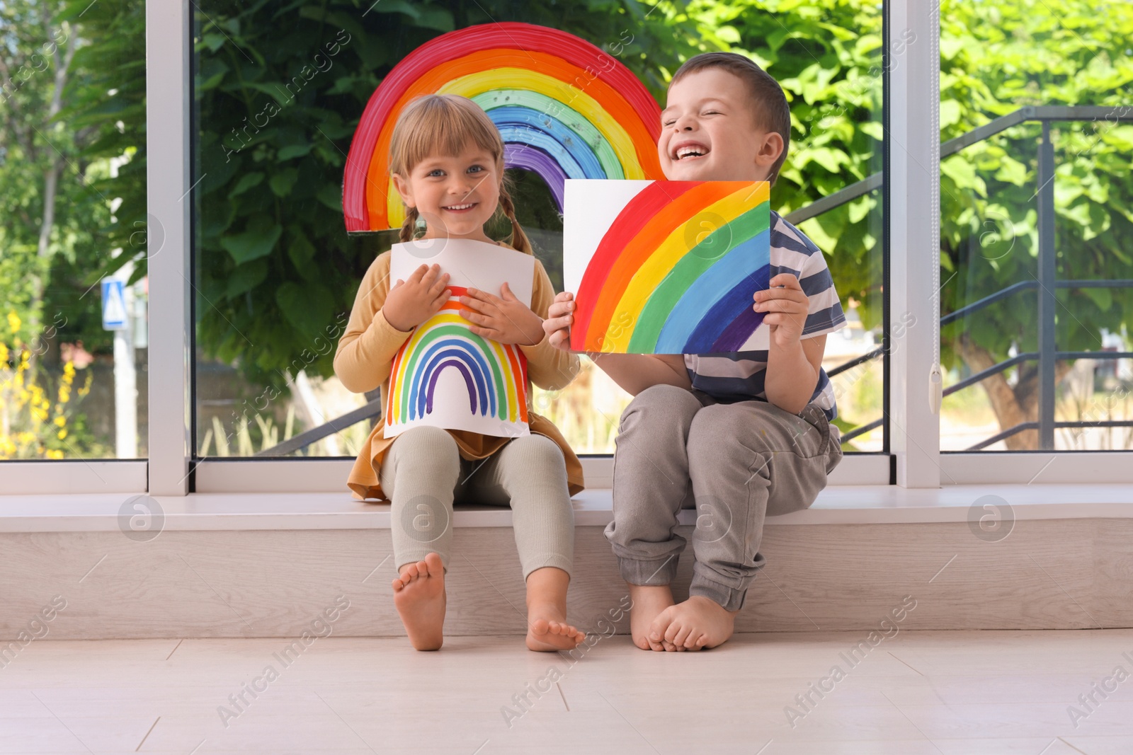 Photo of Children with pictures of rainbow near window indoors