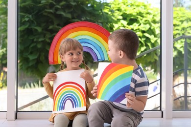 Photo of Children with pictures of rainbow near window indoors