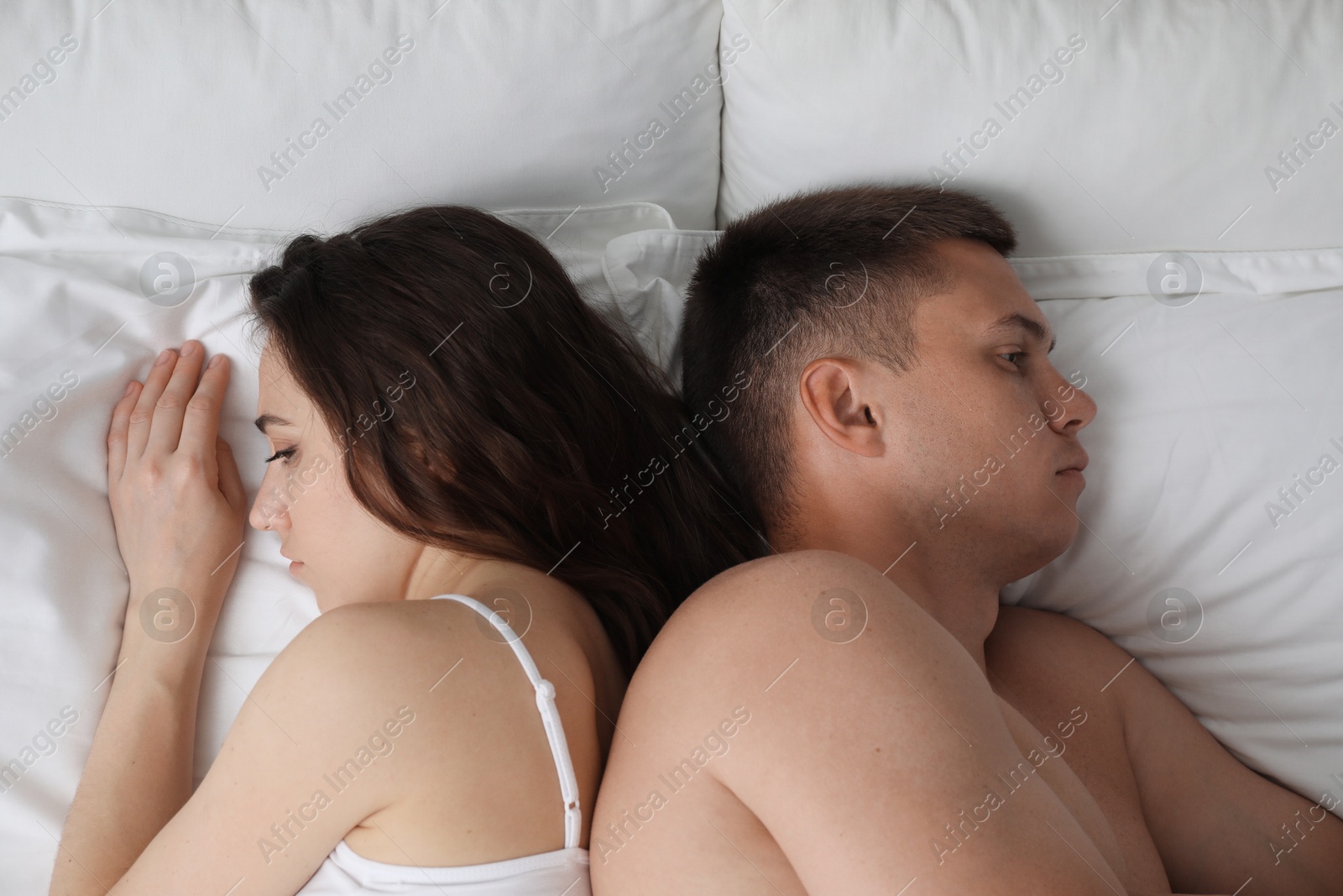 Photo of Offended couple after quarrel ignoring each other on bed, top view. Relationship problem