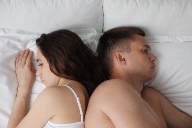 Offended couple after quarrel ignoring each other on bed, top view. Relationship problem