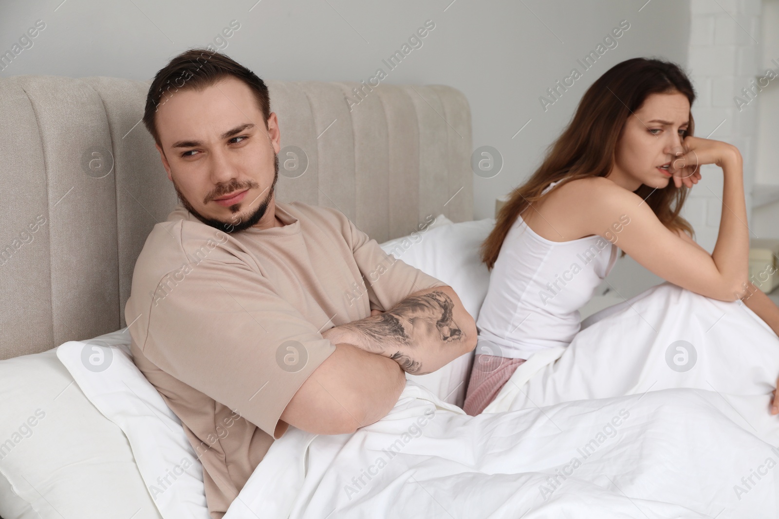 Photo of Offended couple after quarrel ignoring each other in bedroom. Relationship problem