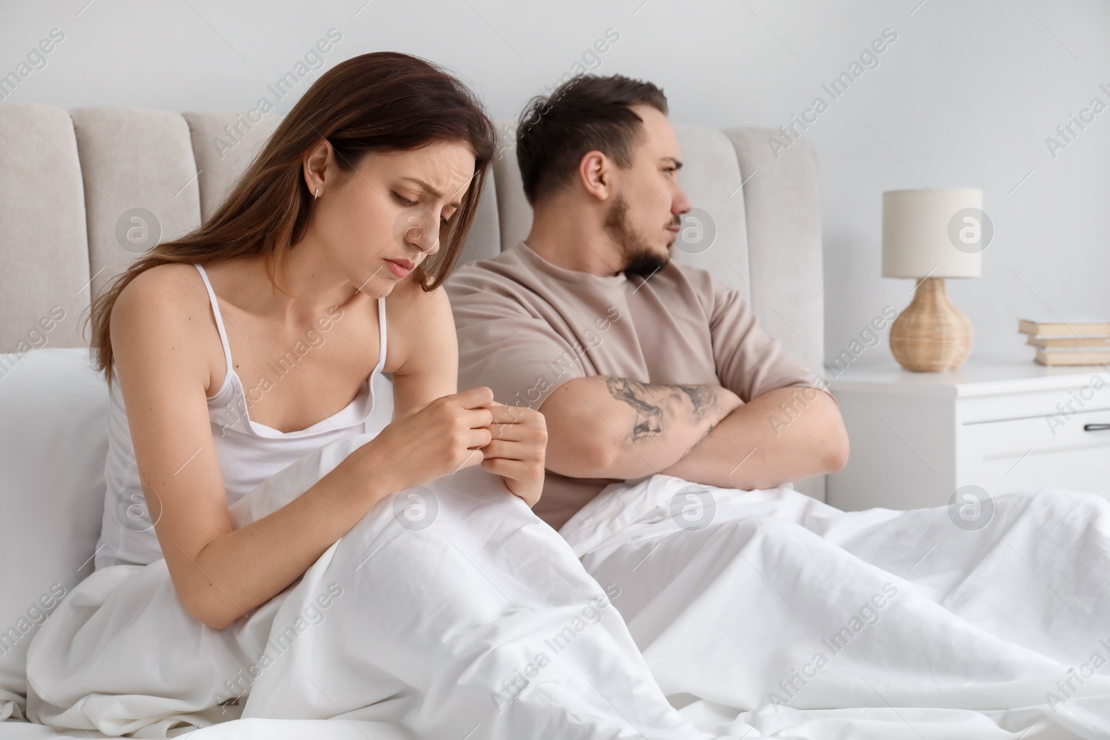 Photo of Offended couple after quarrel ignoring each other in bedroom. Relationship problem