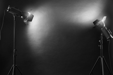 Photo of Dark photo background and professional lighting equipment in studio