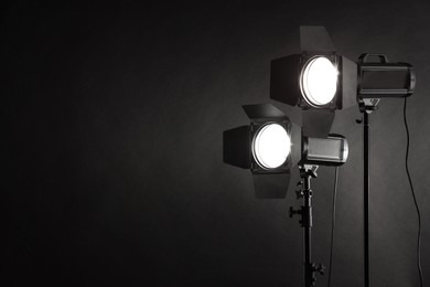 Dark photo background and professional lighting equipment in studio. Space for text