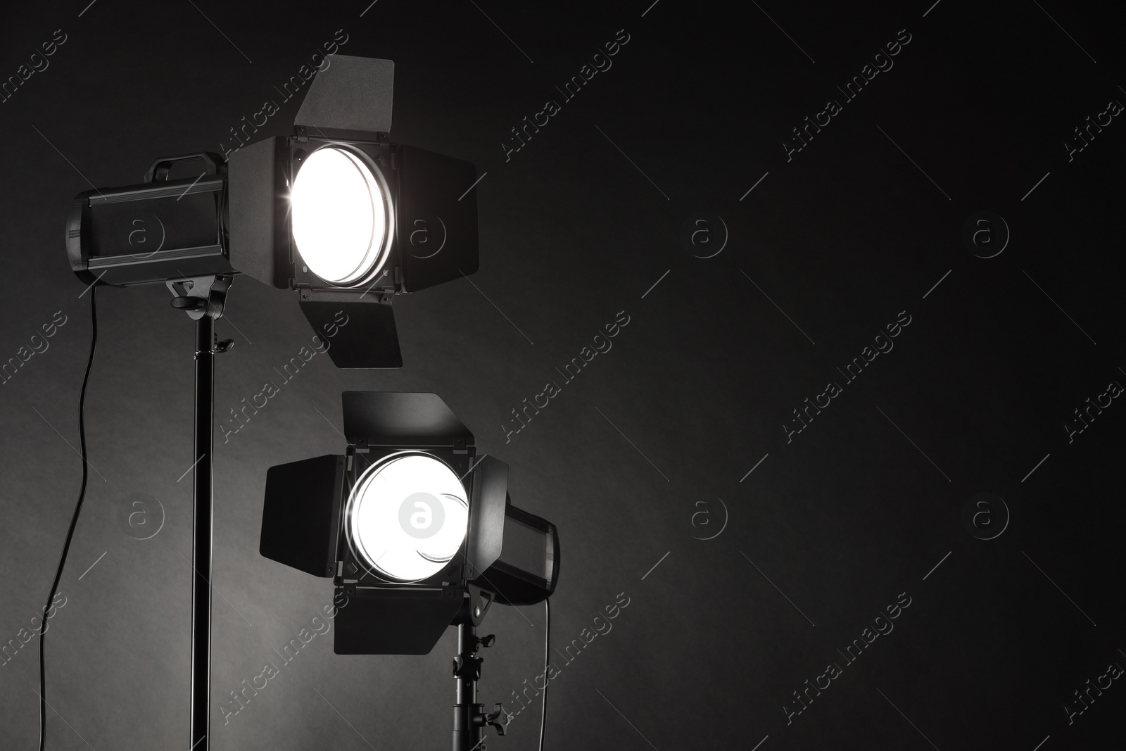 Photo of Dark photo background and professional lighting equipment in studio. Space for text