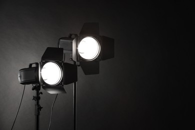 Photo of Dark photo background and professional lighting equipment in studio. Space for text