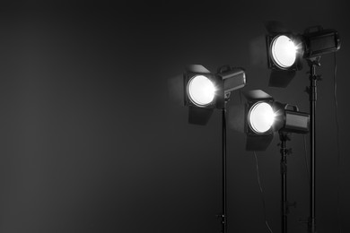 Photo of Dark photo background and professional lighting equipment in studio. Space for text