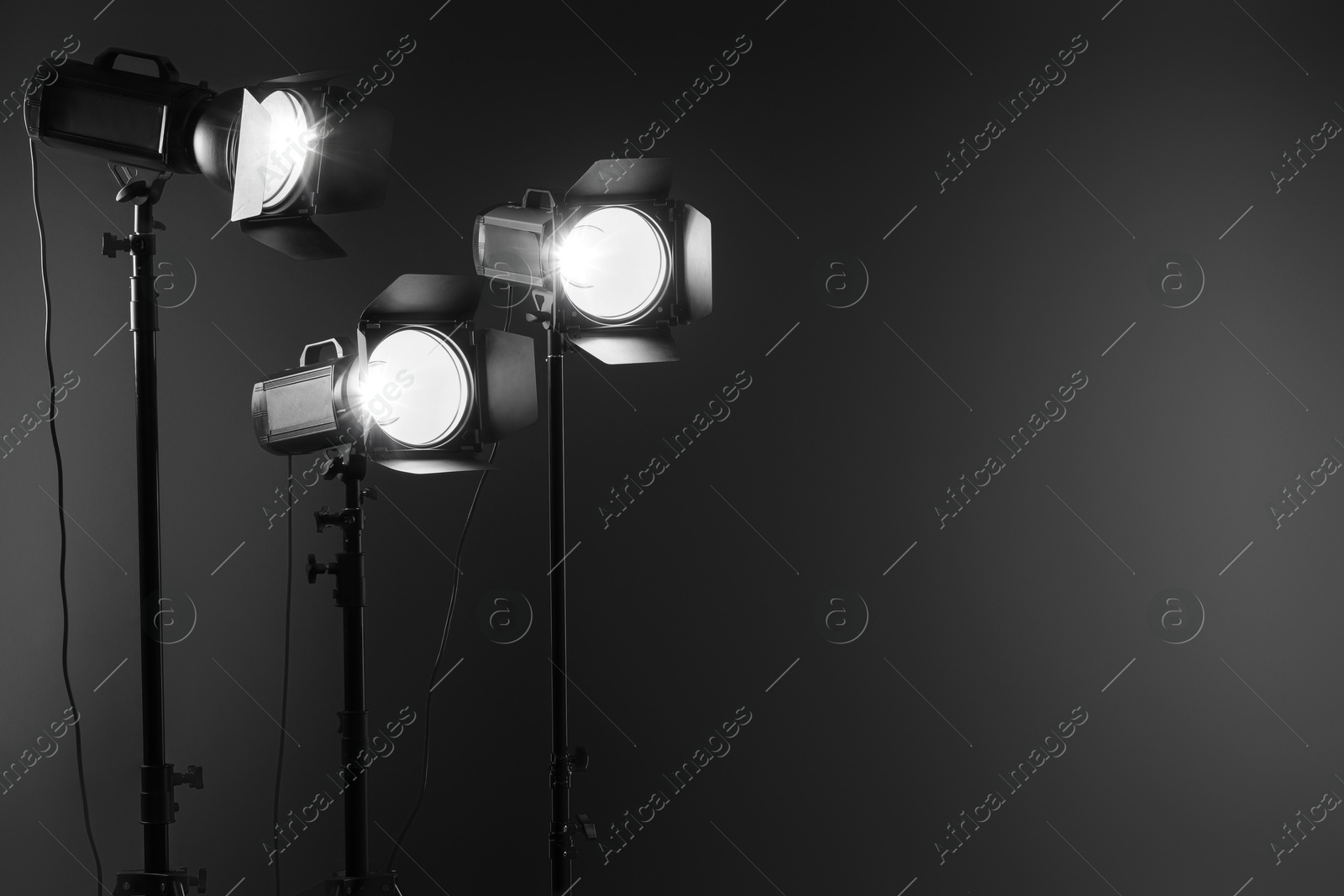 Photo of Dark photo background and professional lighting equipment in studio. Space for text