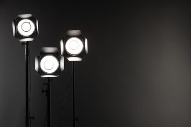 Dark photo background and professional lighting equipment in studio. Space for text