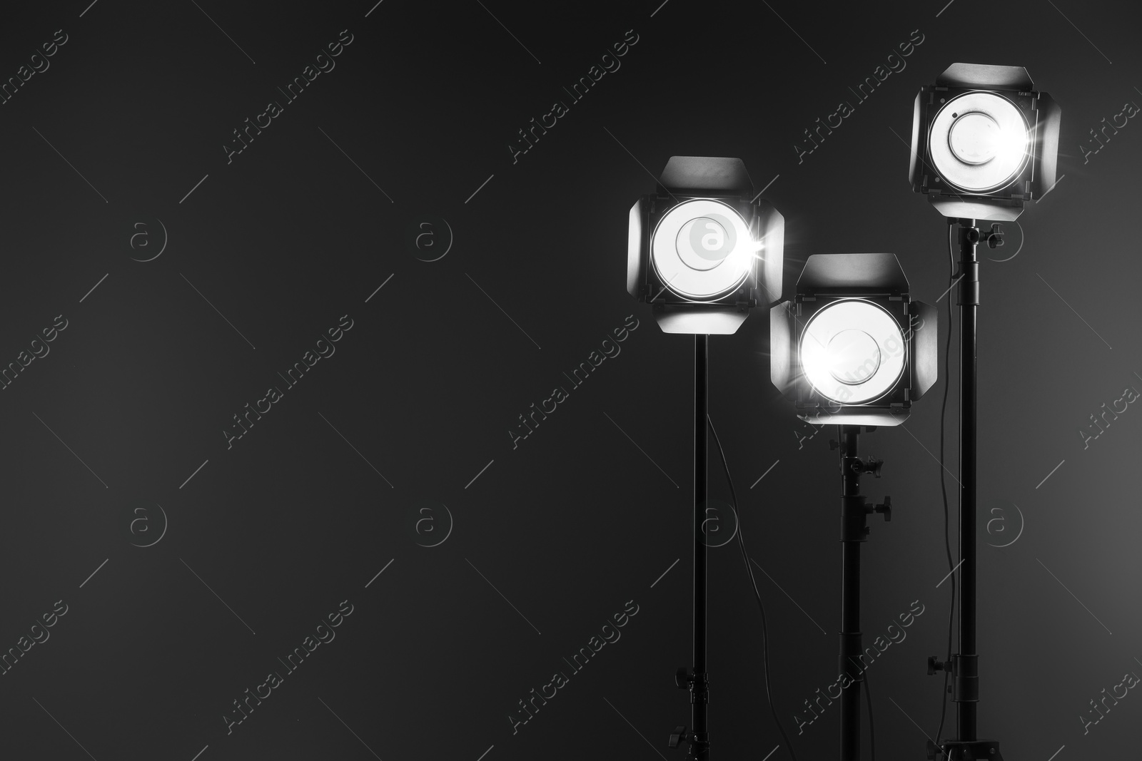 Photo of Dark photo background and professional lighting equipment in studio. Space for text