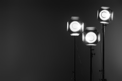 Dark photo background and professional lighting equipment in studio. Space for text