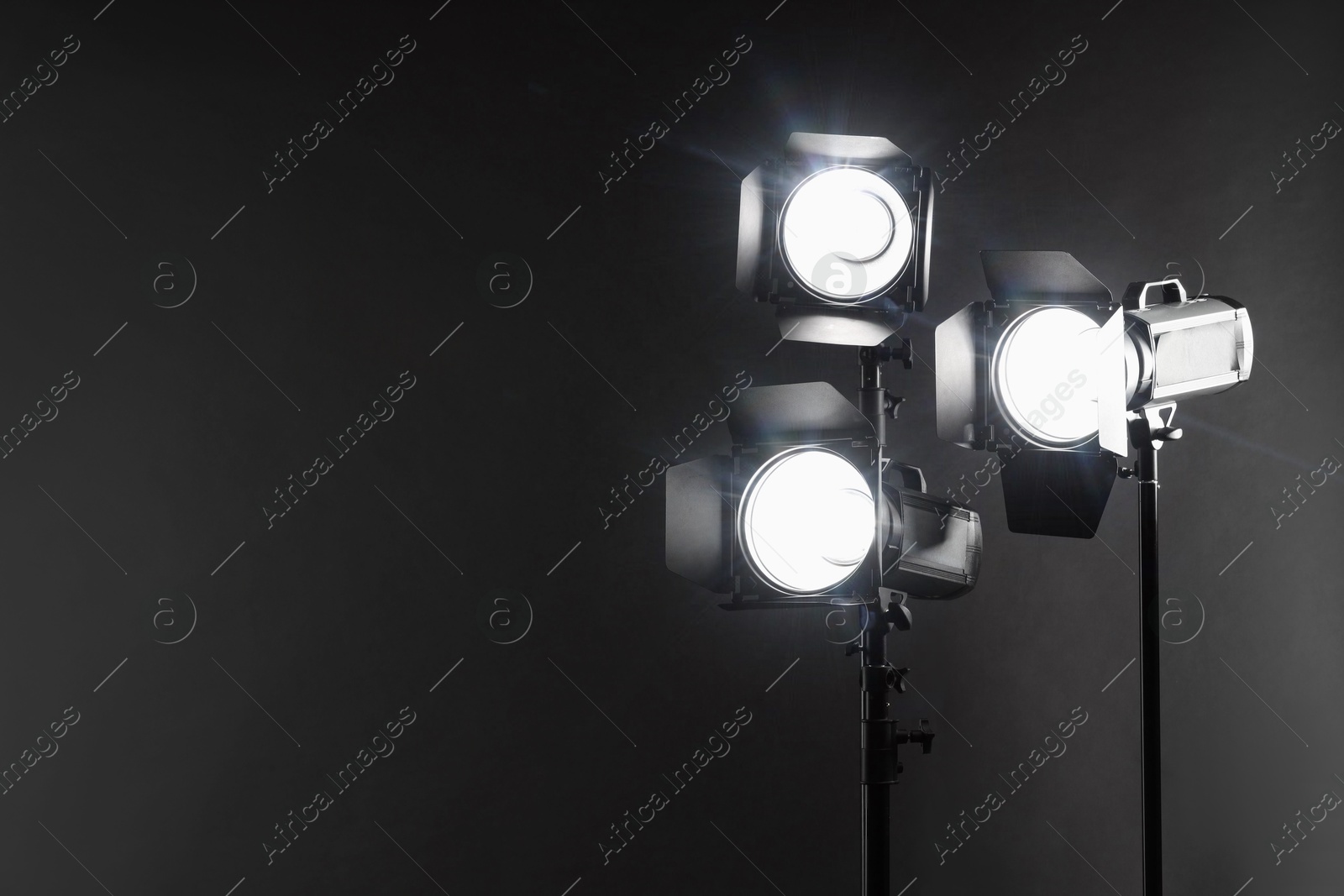 Photo of Dark photo background and professional lighting equipment in studio. Space for text