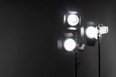 Photo of Dark photo background and professional lighting equipment in studio. Space for text