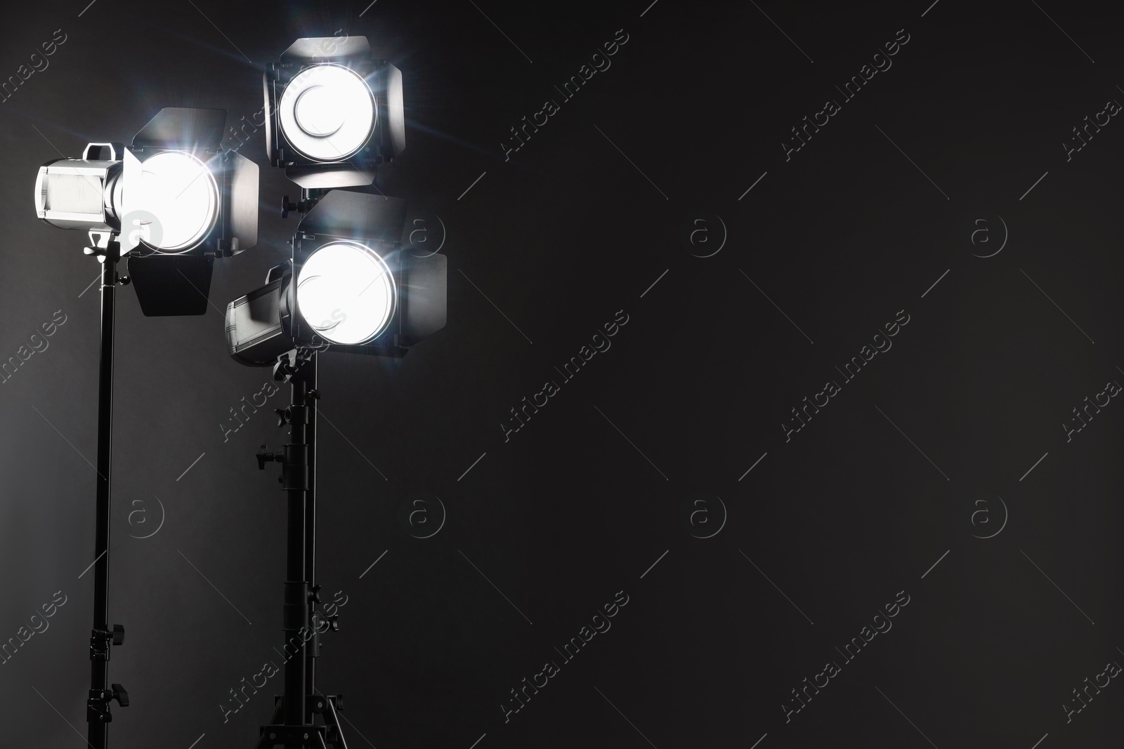 Photo of Dark photo background and professional lighting equipment in studio. Space for text