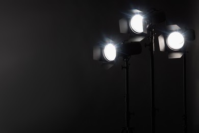 Photo of Dark photo background and professional lighting equipment in studio. Space for text