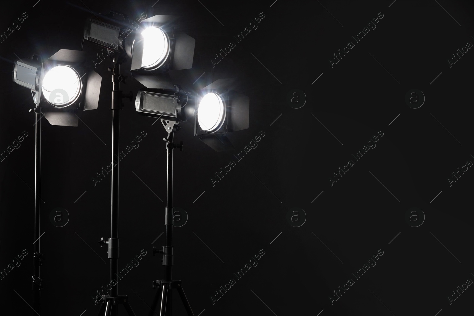 Photo of Dark photo background and professional lighting equipment in studio. Space for text