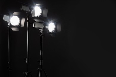 Dark photo background and professional lighting equipment in studio. Space for text