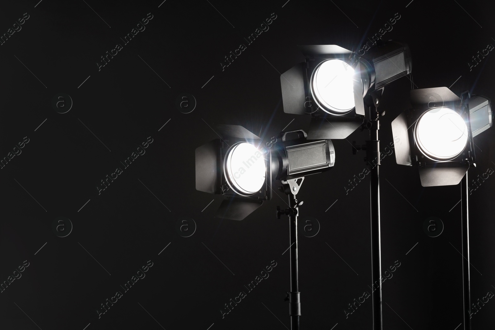 Photo of Dark photo background and professional lighting equipment in studio. Space for text