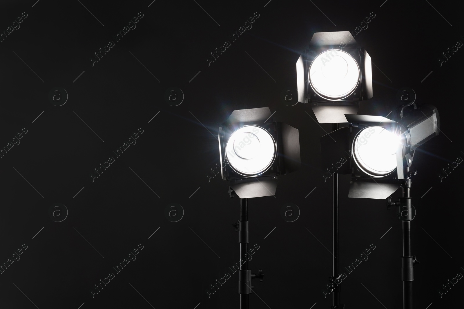 Photo of Dark photo background and professional lighting equipment in studio. Space for text