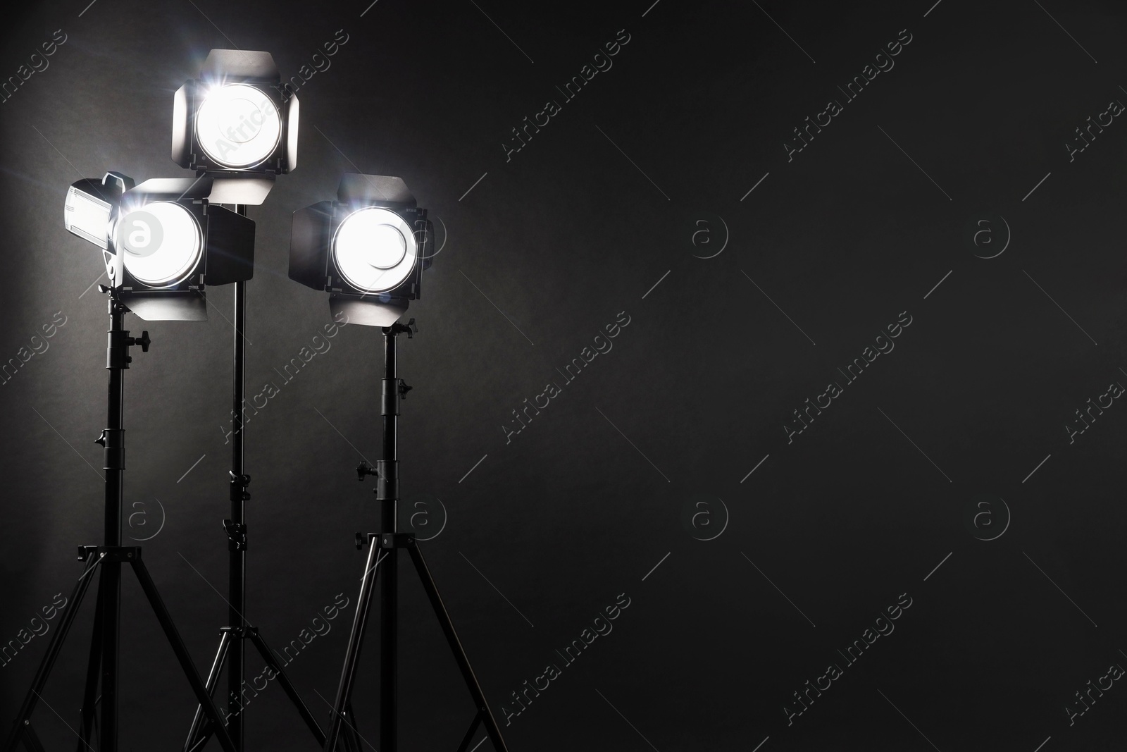 Photo of Dark photo background and professional lighting equipment in studio. Space for text