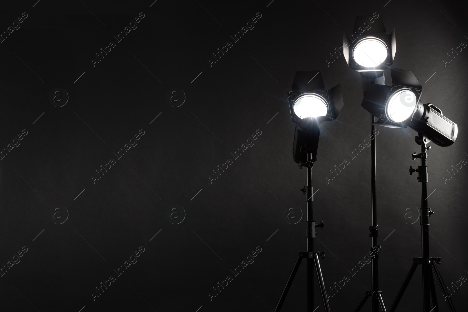 Photo of Dark photo background and professional lighting equipment in studio. Space for text