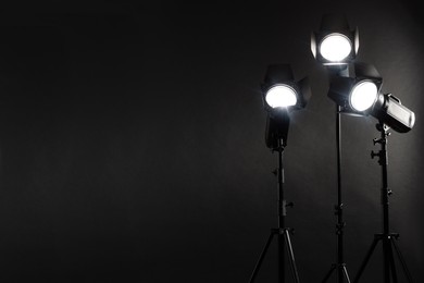 Dark photo background and professional lighting equipment in studio. Space for text