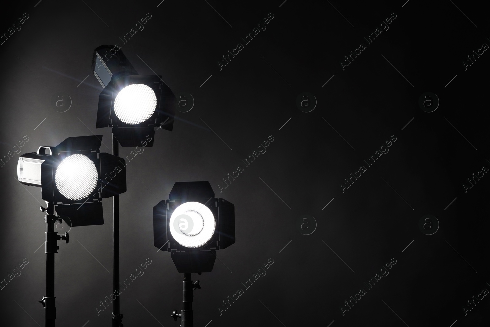 Photo of Dark photo background and professional lighting equipment in studio. Space for text