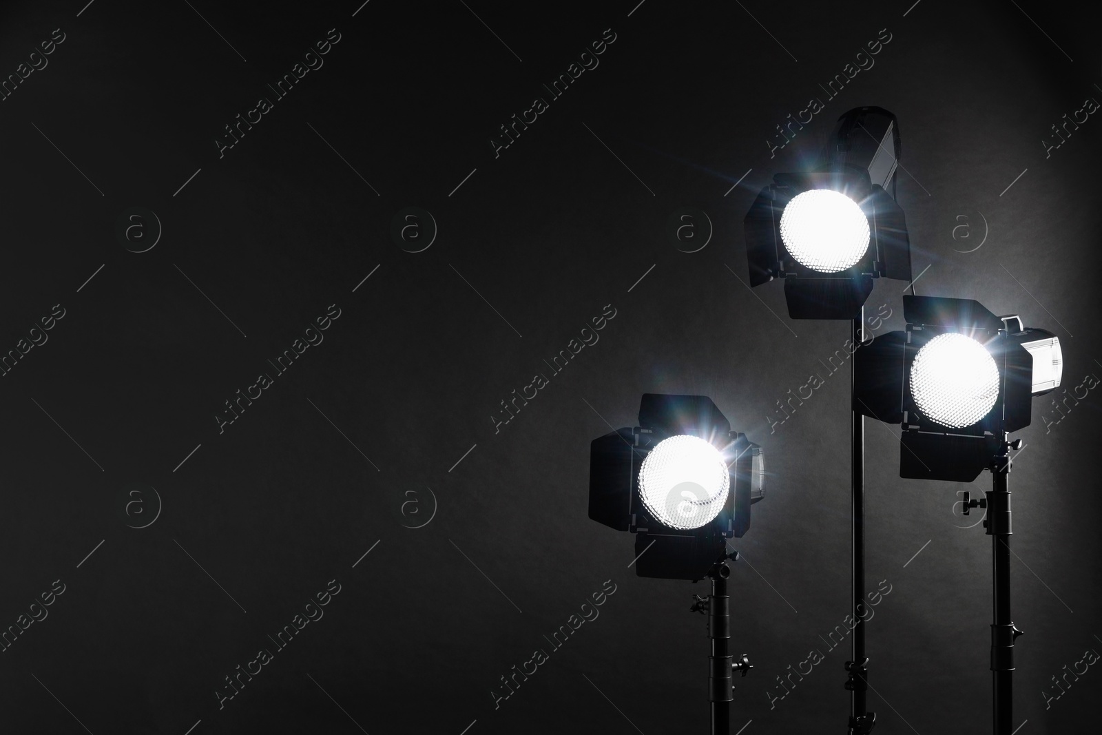 Photo of Dark photo background and professional lighting equipment in studio. Space for text
