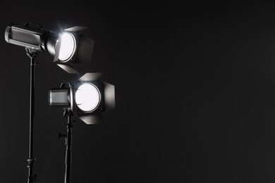 Photo of Dark photo background and professional lighting equipment in studio. Space for text