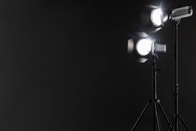 Dark photo background and professional lighting equipment in studio. Space for text