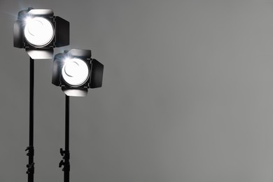 Photo of Grey photo background and professional lighting equipment in studio. Space for text