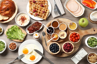 Photo of Different meals served for breakfast on wooden table, flat lay