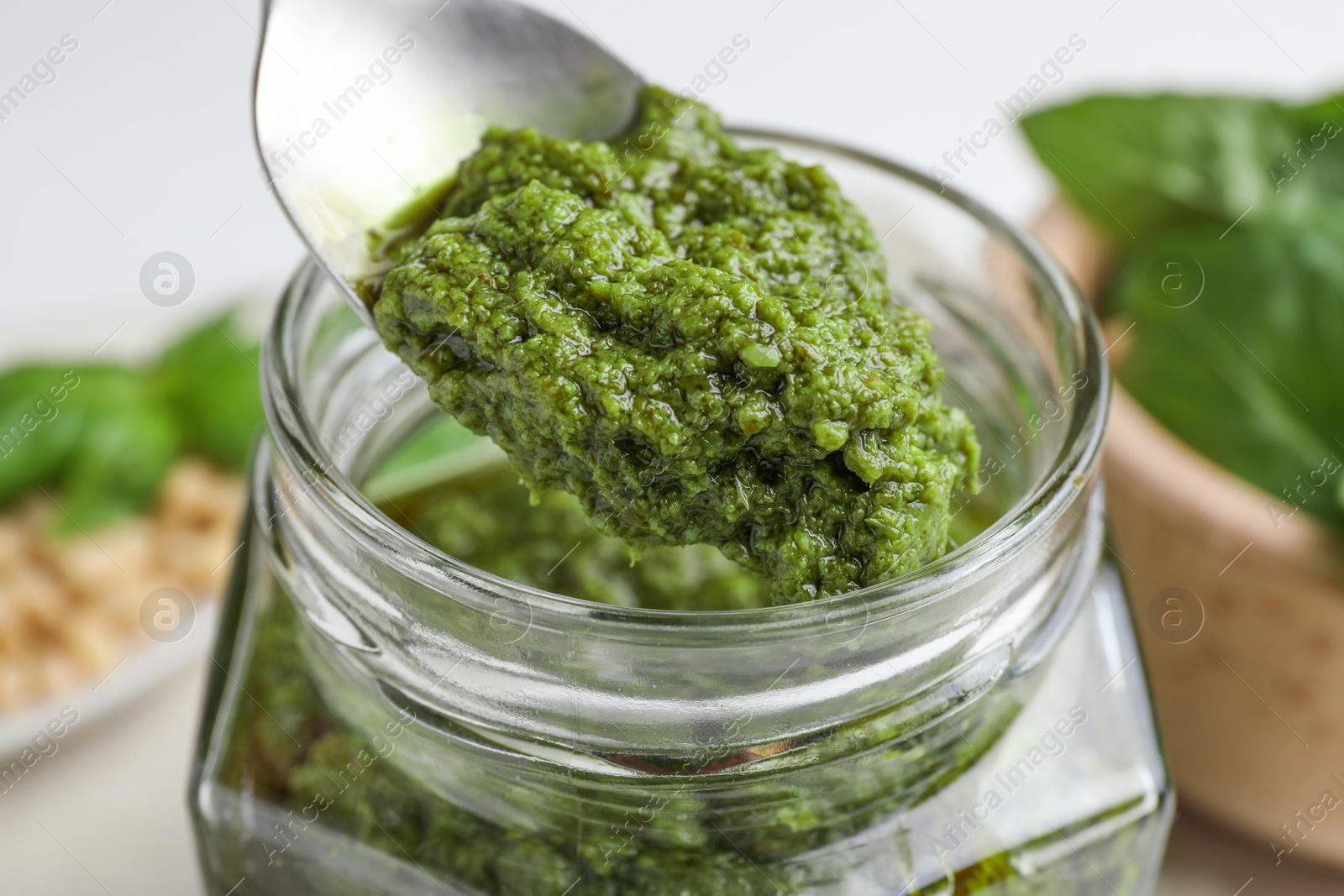 Photo of Taking tasty pesto sauce at table, closeup