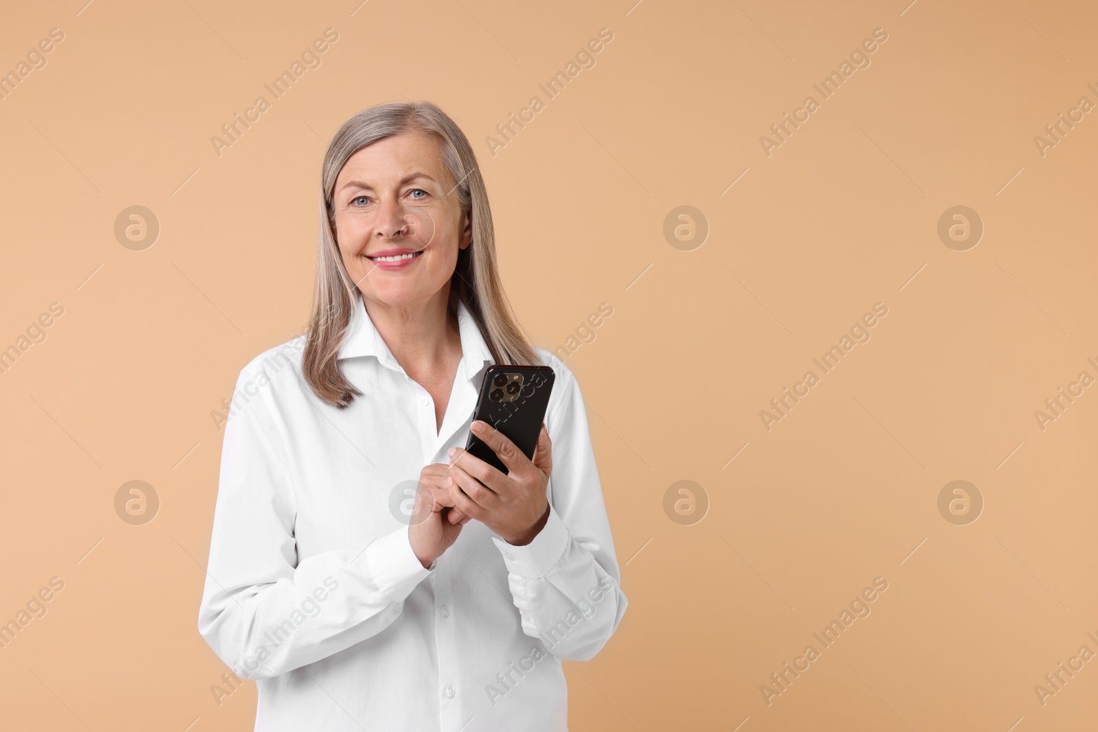 Photo of Senior woman with phone on beige background, space for text