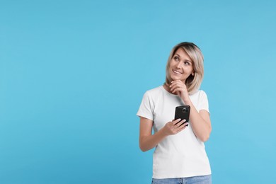 Photo of Happy woman with phone on light blue background, space for text