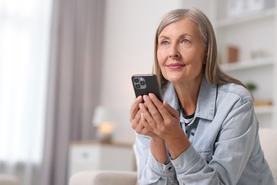 Photo of Senior woman using mobile phone at home, space for text