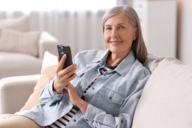 Photo of Senior woman using mobile phone at home