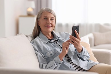 Senior woman using mobile phone at home