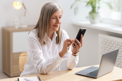 Senior woman using mobile phone at home