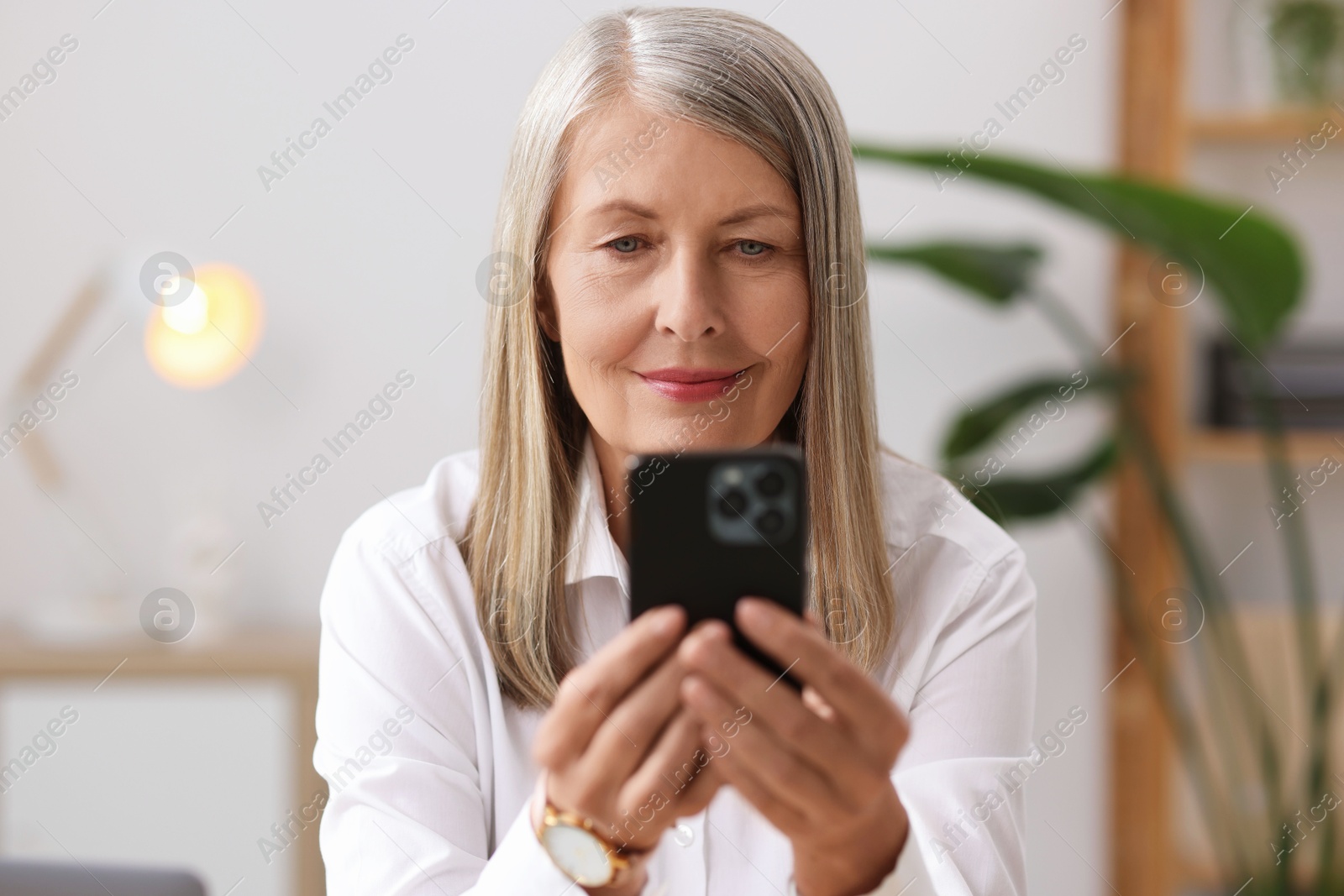 Photo of Senior woman using mobile phone at home