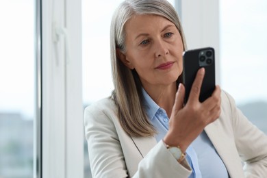 Photo of Senior woman using mobile phone at home