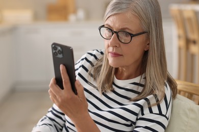 Senior woman using mobile phone at home