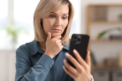 Woman using modern mobile phone at home