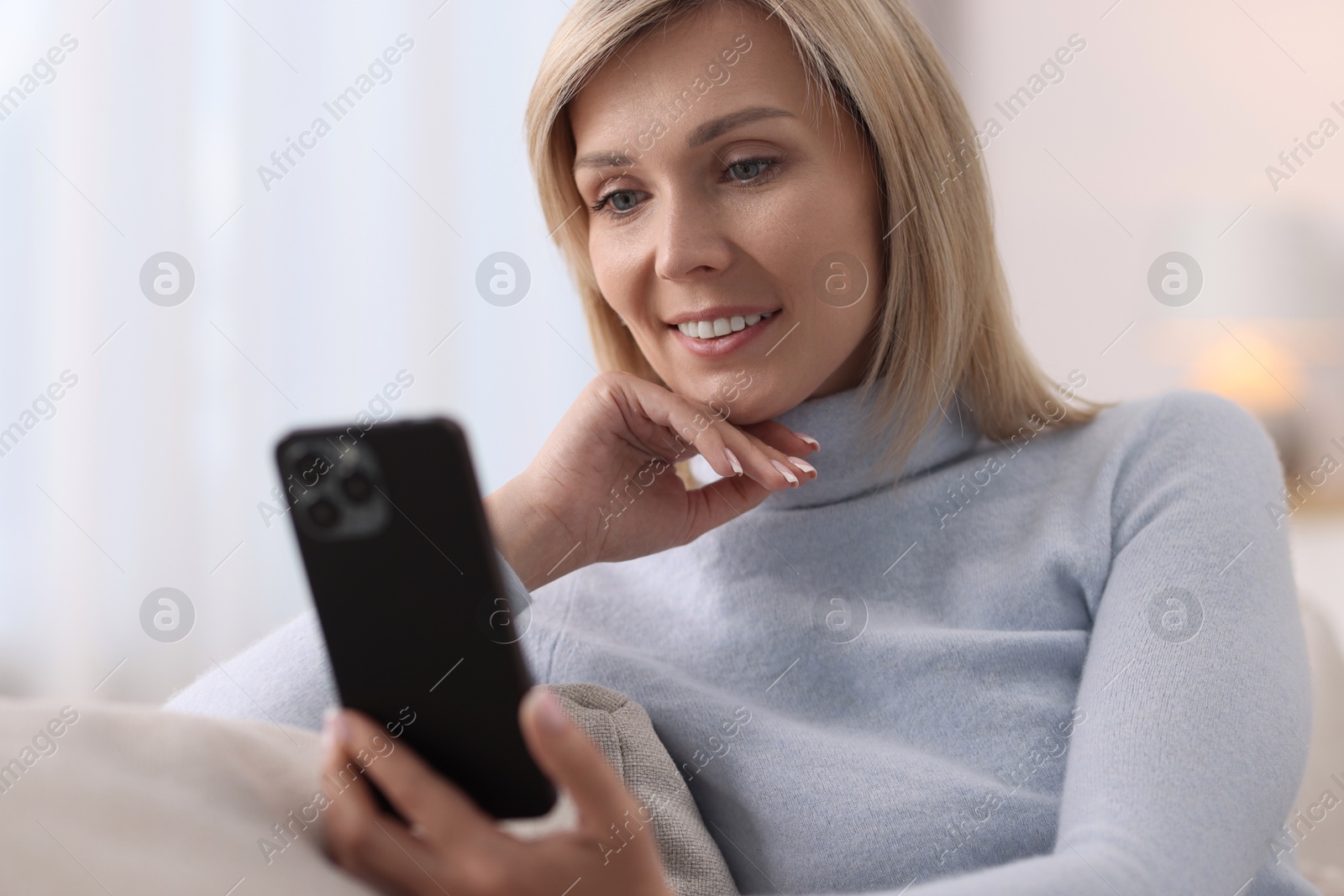 Photo of Happy woman using mobile phone at home