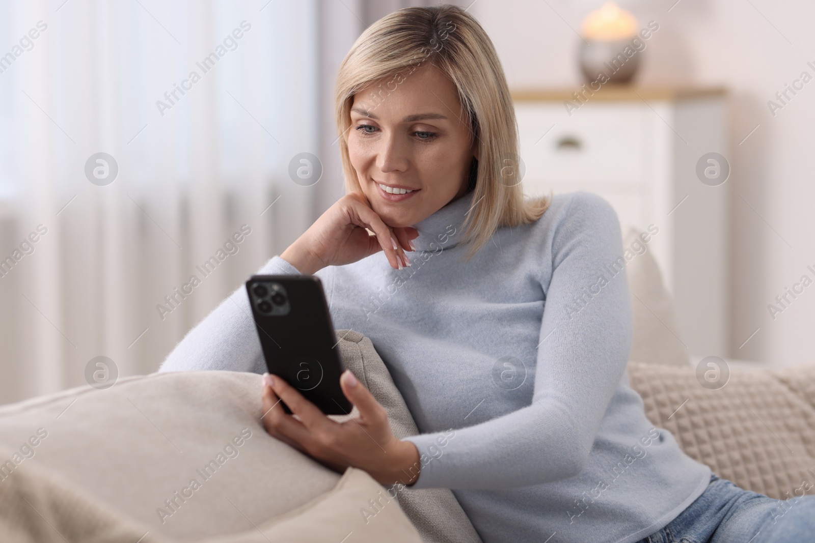 Photo of Happy woman using mobile phone at home